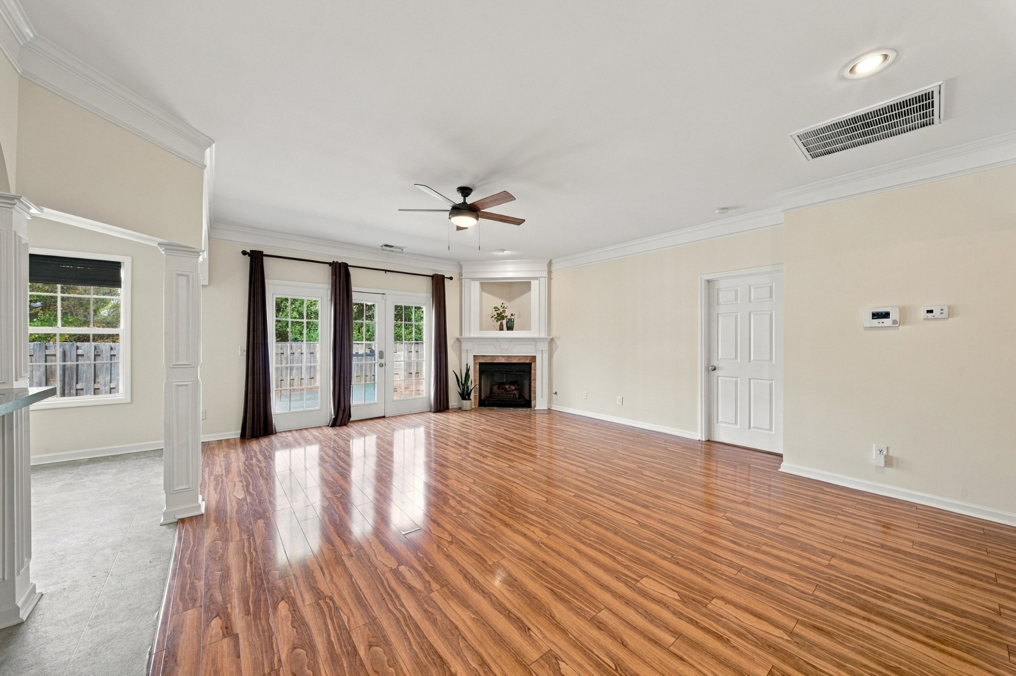 Living room with polished wood floors, a fireplace, and French doors opening to a fenced patio.