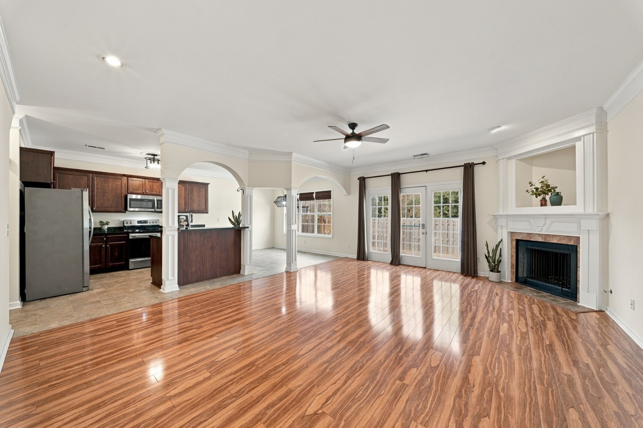 Open-plan living room and kitchen with wood floors, a fireplace, and French doors.