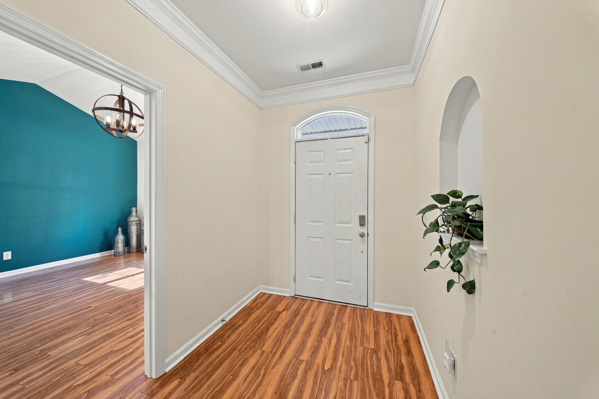 Entry foyer with warm wood flooring, a white front door, and an arched transom.