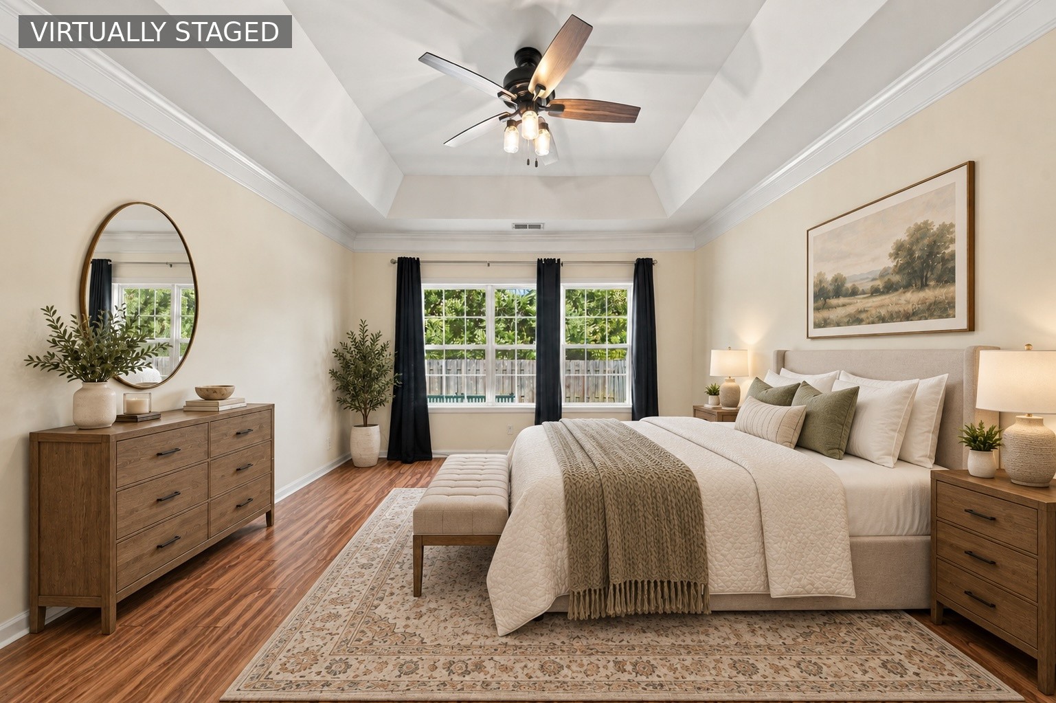 Virtually staged bedroom with a king-size bed, wood dressers, and a tray ceiling with a ceiling fan.