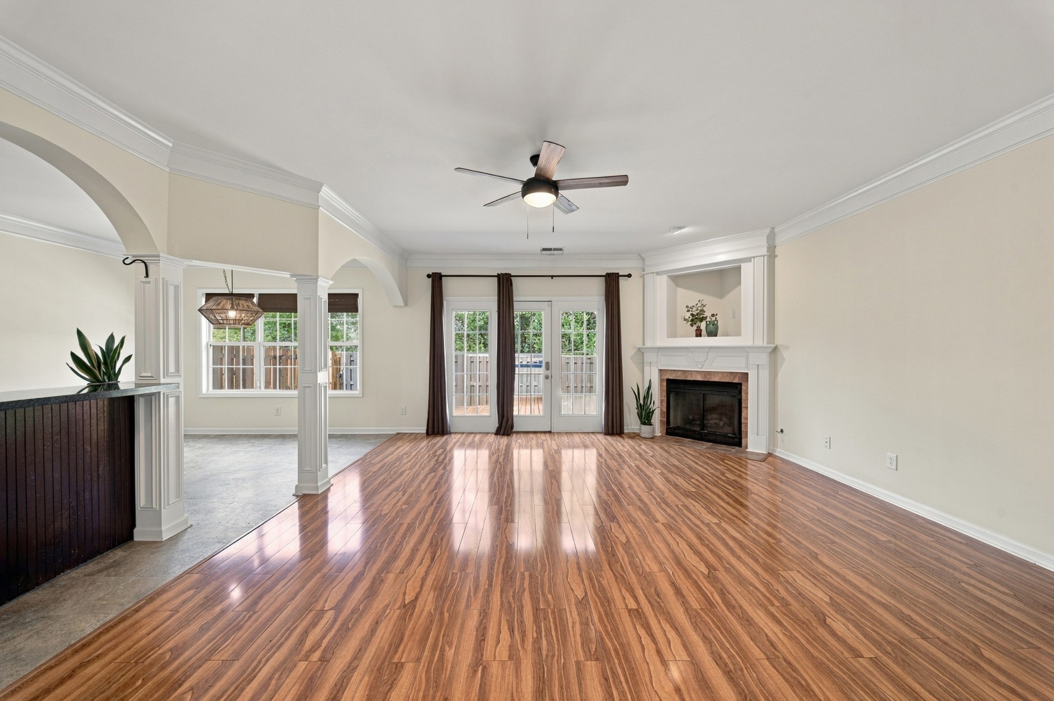 Open-plan living room with glossy wood-look floors, fireplace, and French doors to the patio.