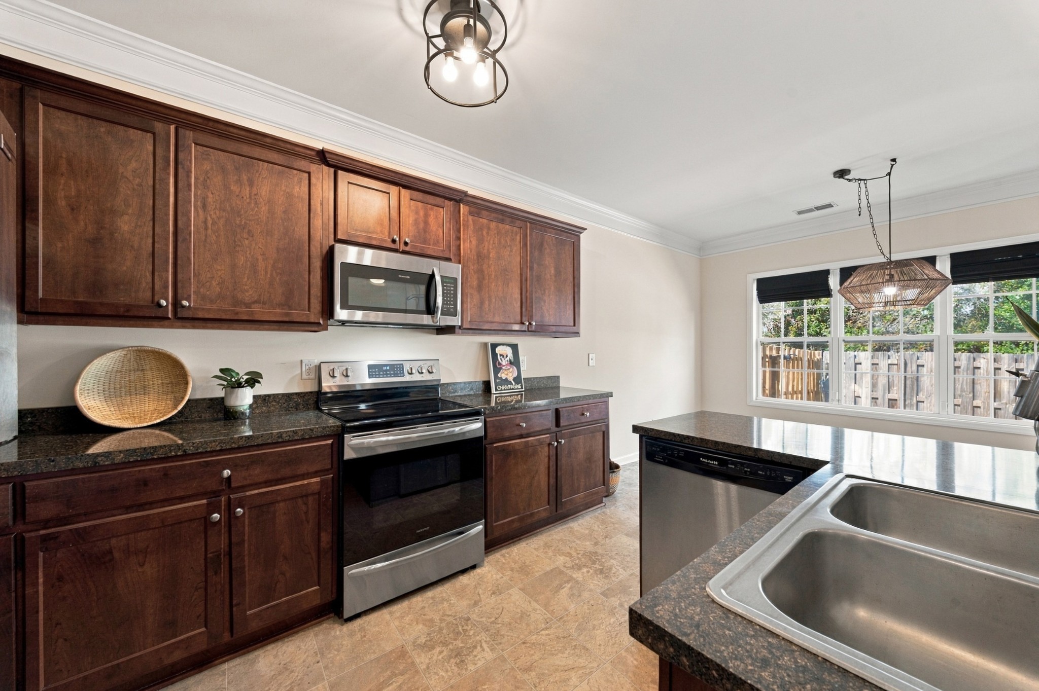 Kitchen with dark wood cabinets, granite counters, stainless steel appliances, and a large island sink.