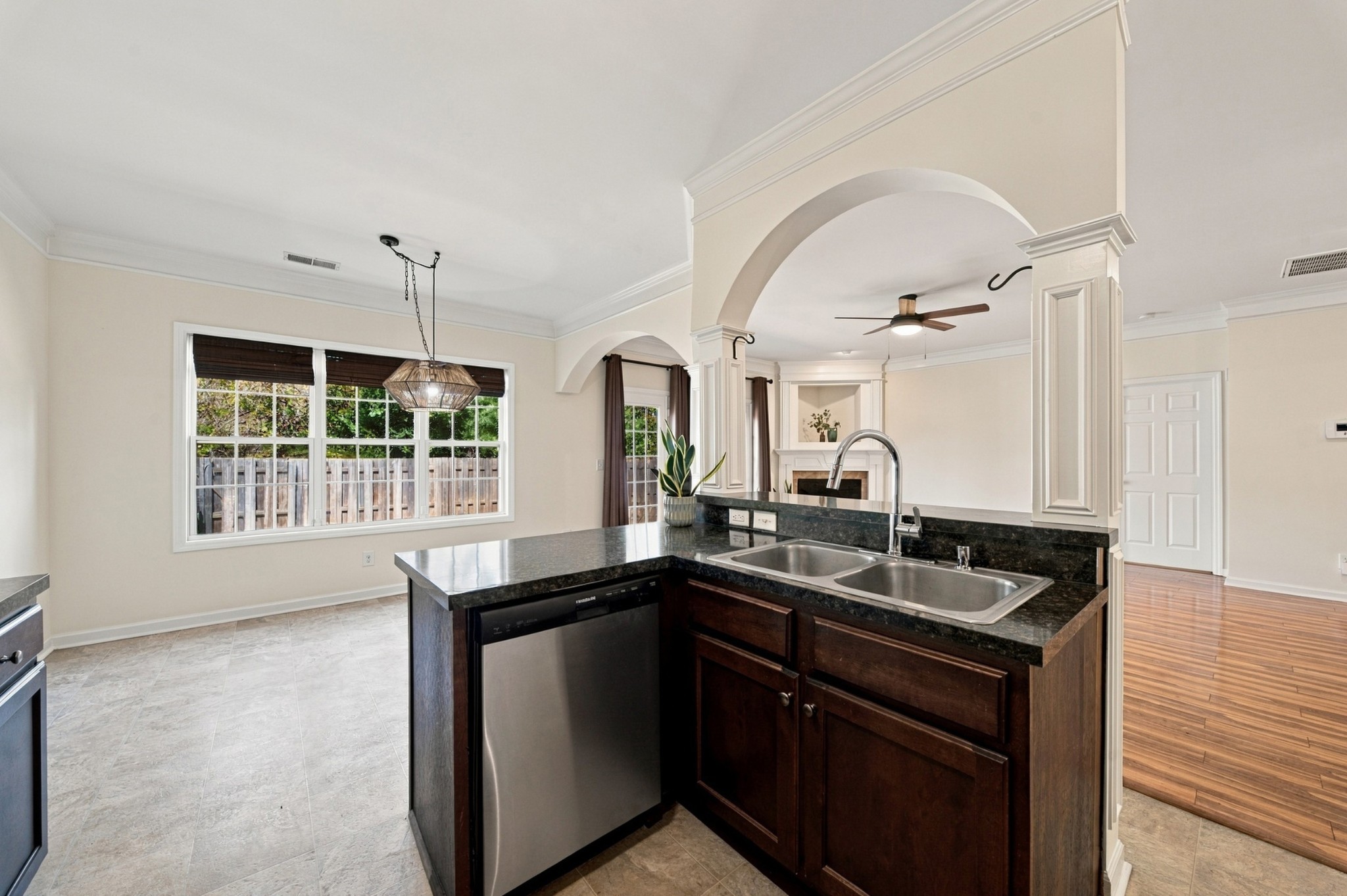 Kitchen with dark wood cabinetry, black granite counters, and a peninsula sink beneath arched openings.
