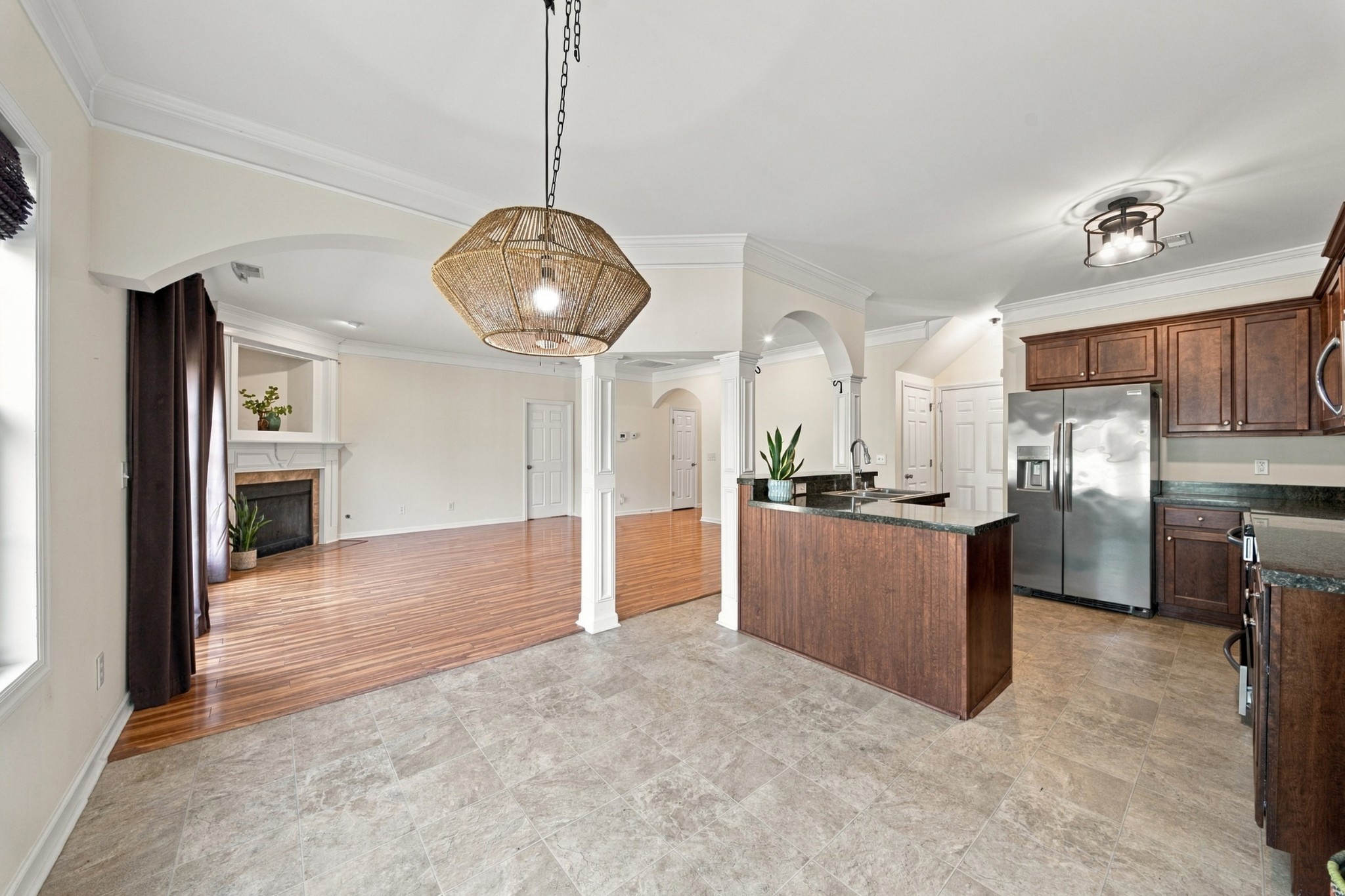 Open kitchen and living area with a stone-topped island, dark wood cabinets, and a fireplace.