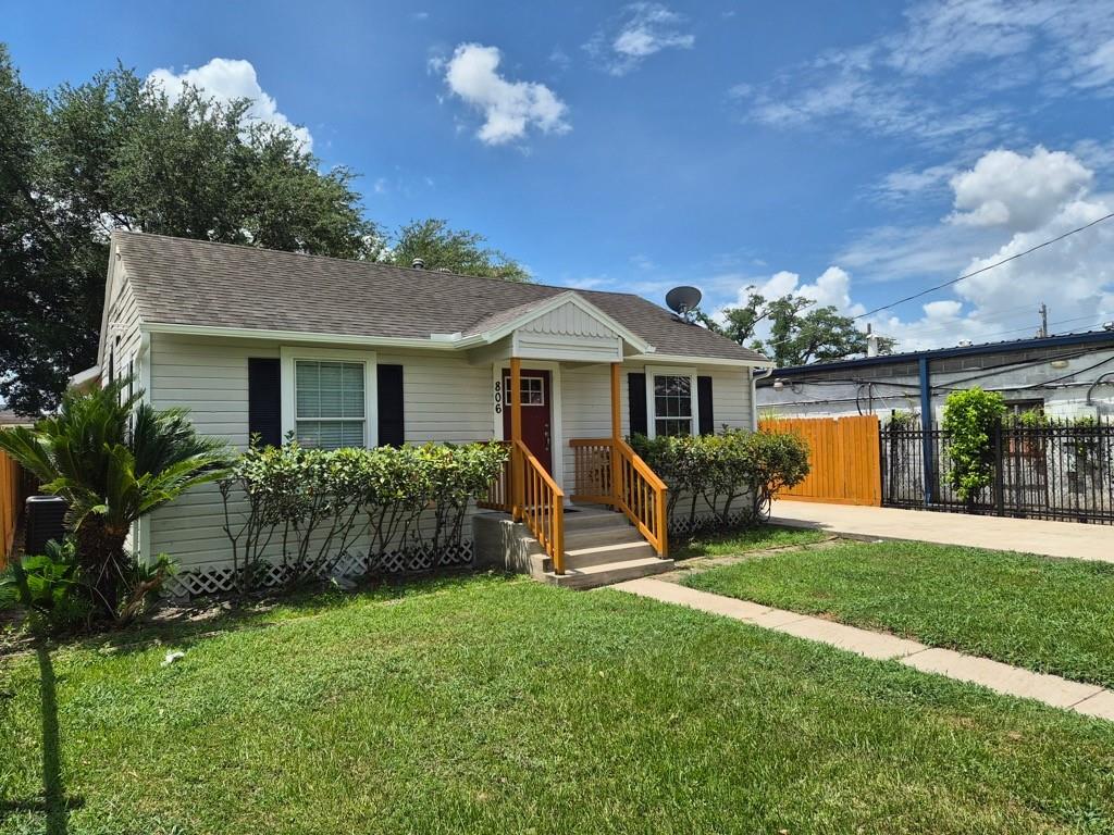 Single-story house with a red front door, orange-toned stair railings, and a broad green lawn.