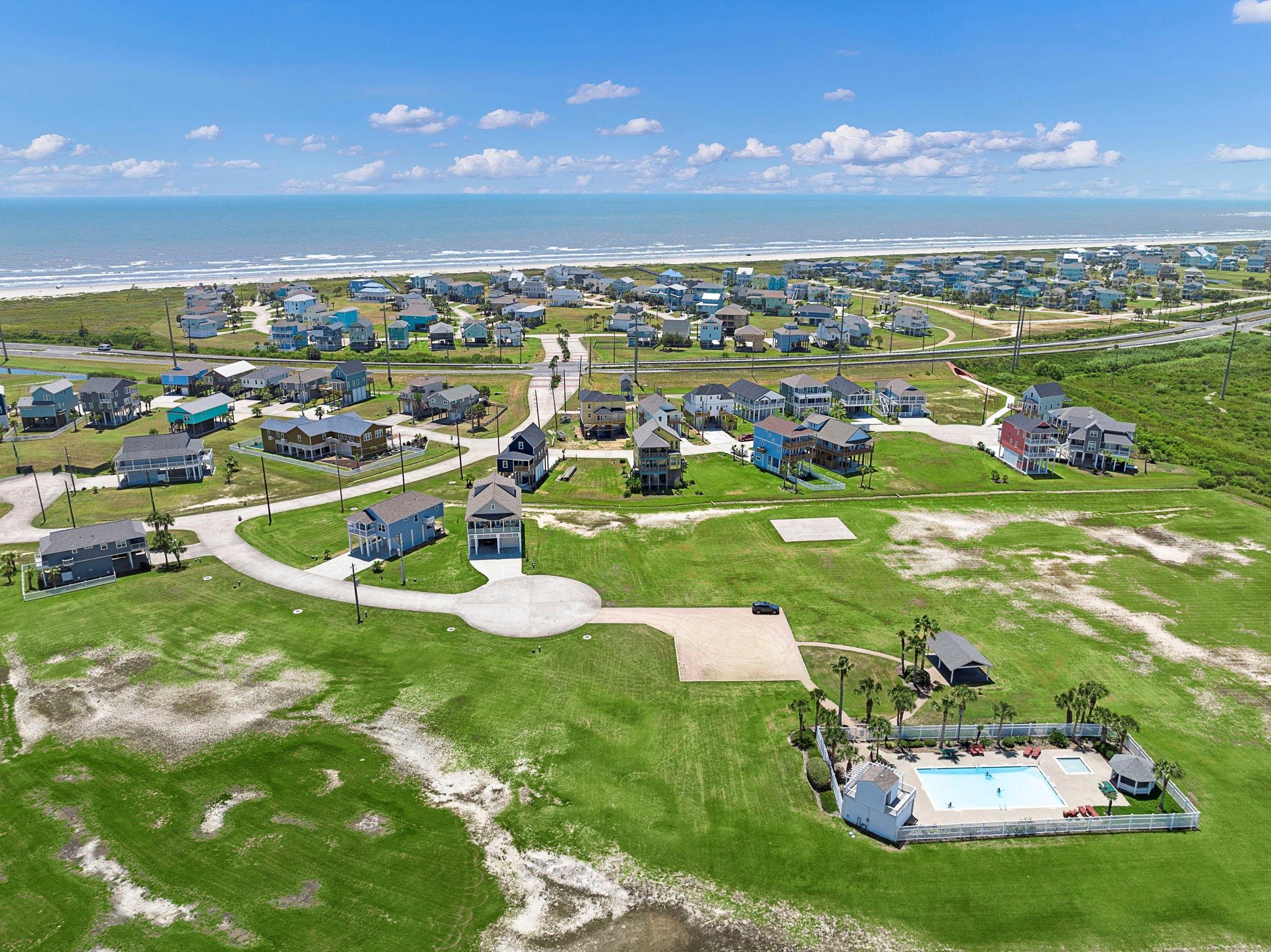 Aerial view of coastal homes and a community pool beside the ocean.