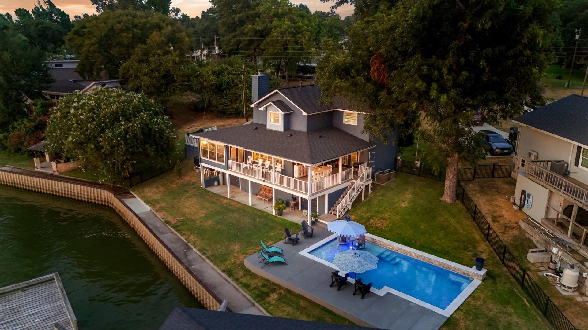 Waterfront home with a broad covered deck and backyard swimming pool beside a canal.