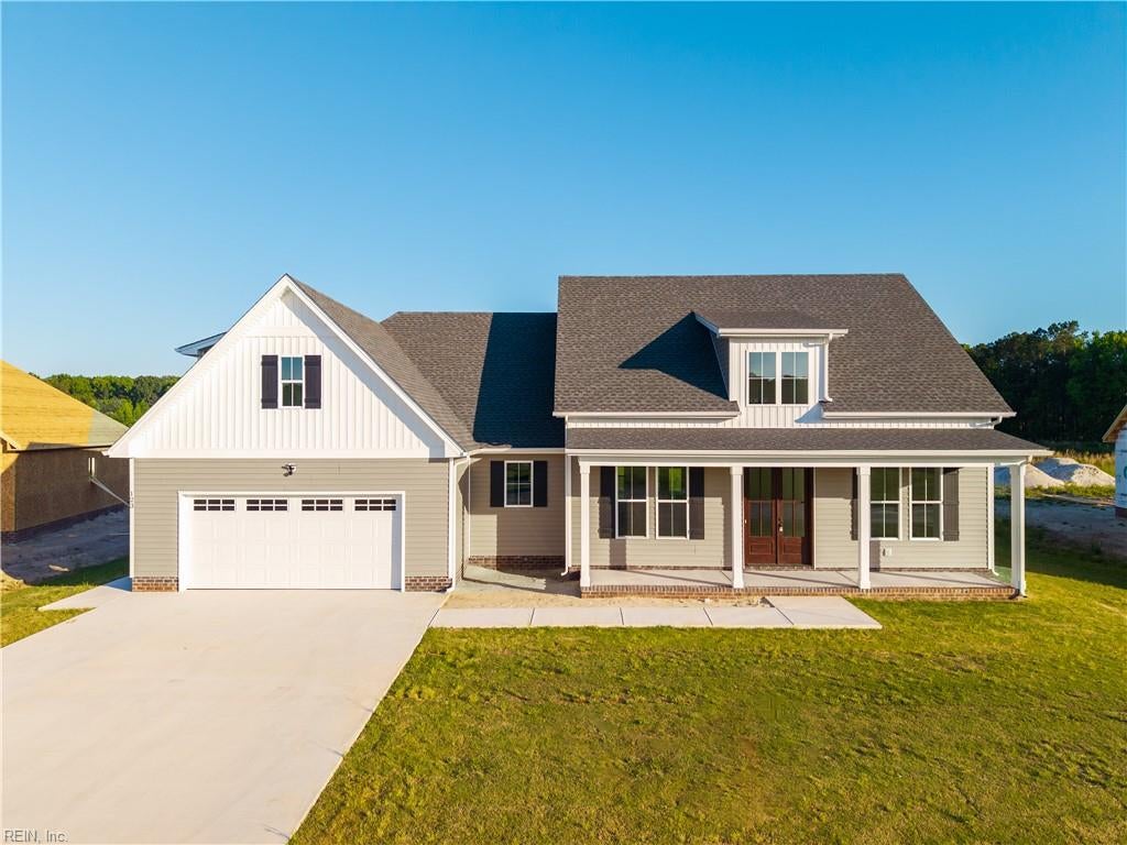 Gray two-story house with a large garage, covered porch, and wide concrete driveway.