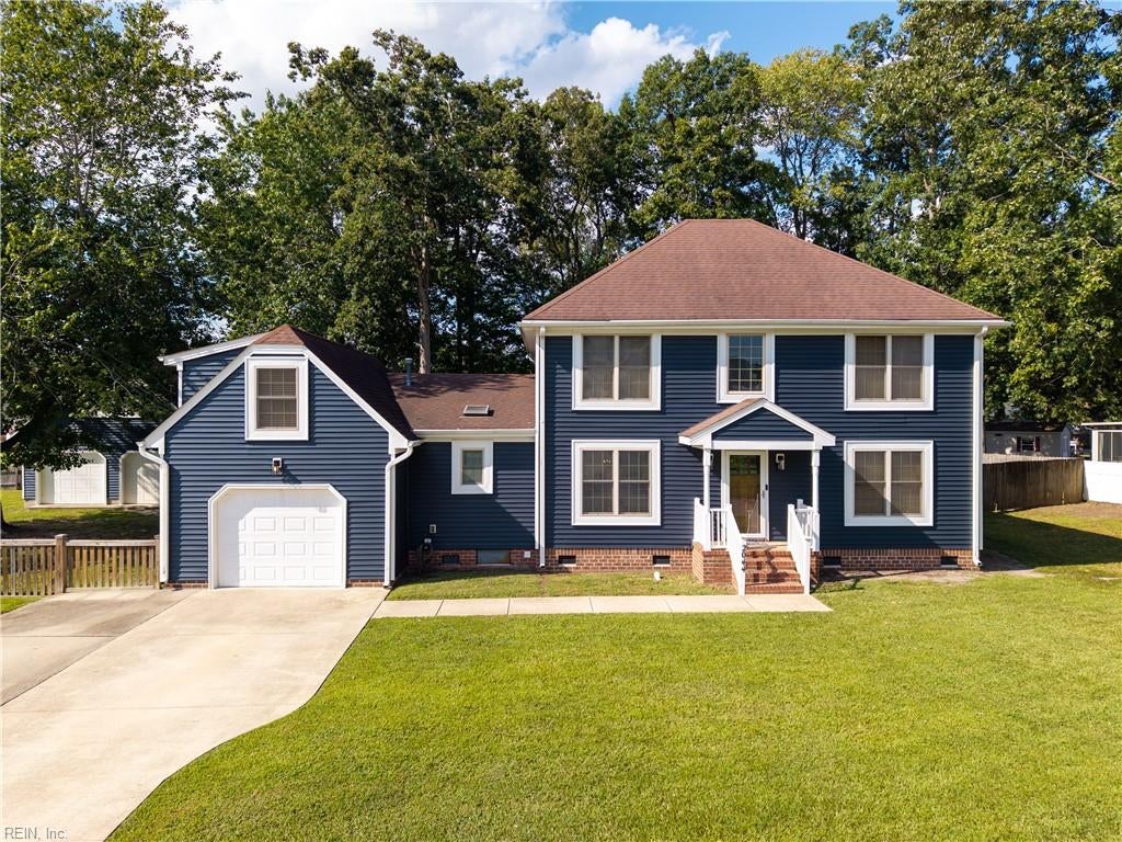 Blue two-story home with white trim, an attached garage, and a broad front lawn.