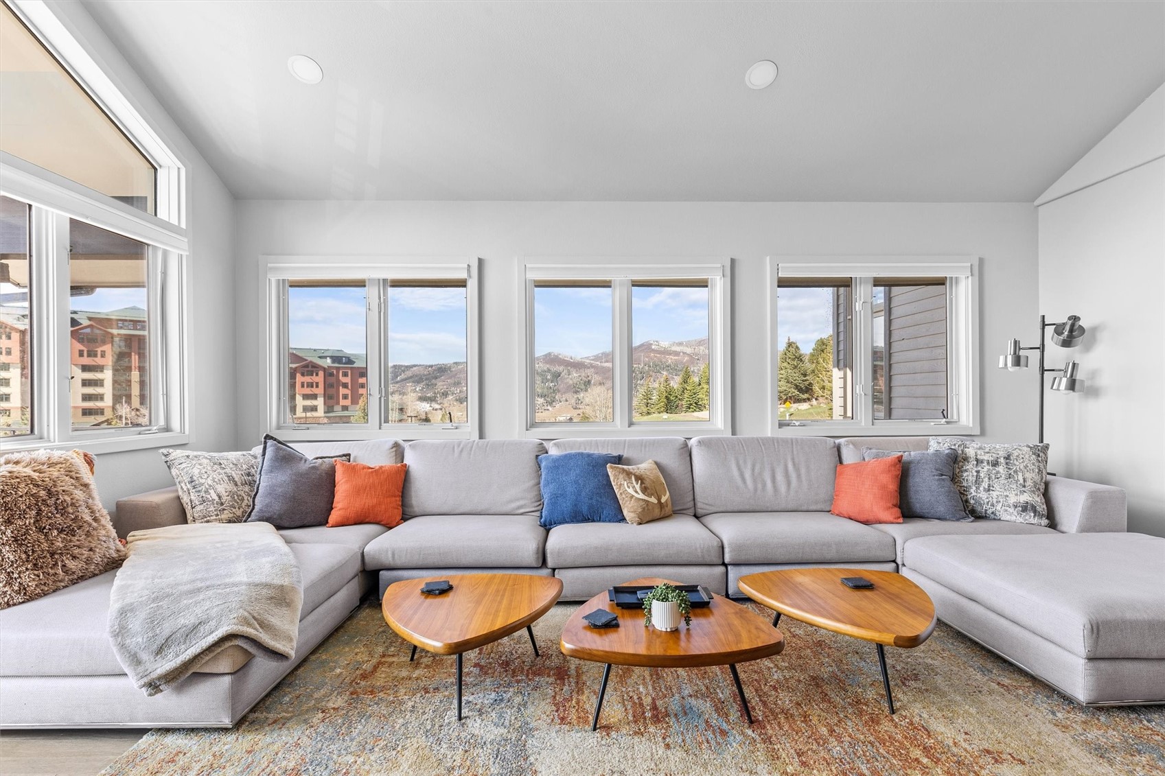 Living room with a large gray sectional and windows overlooking the mountains.