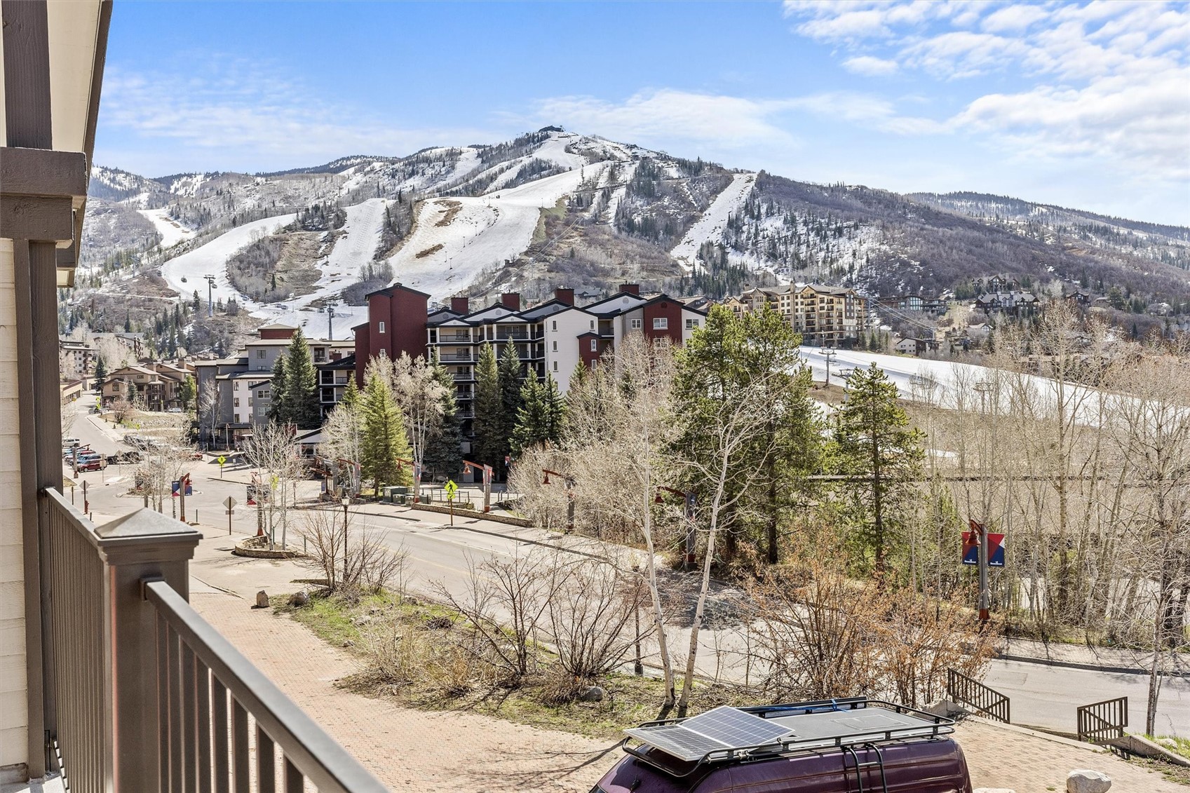 Balcony view across resort buildings to ski slopes and a snow-dusted mountain.