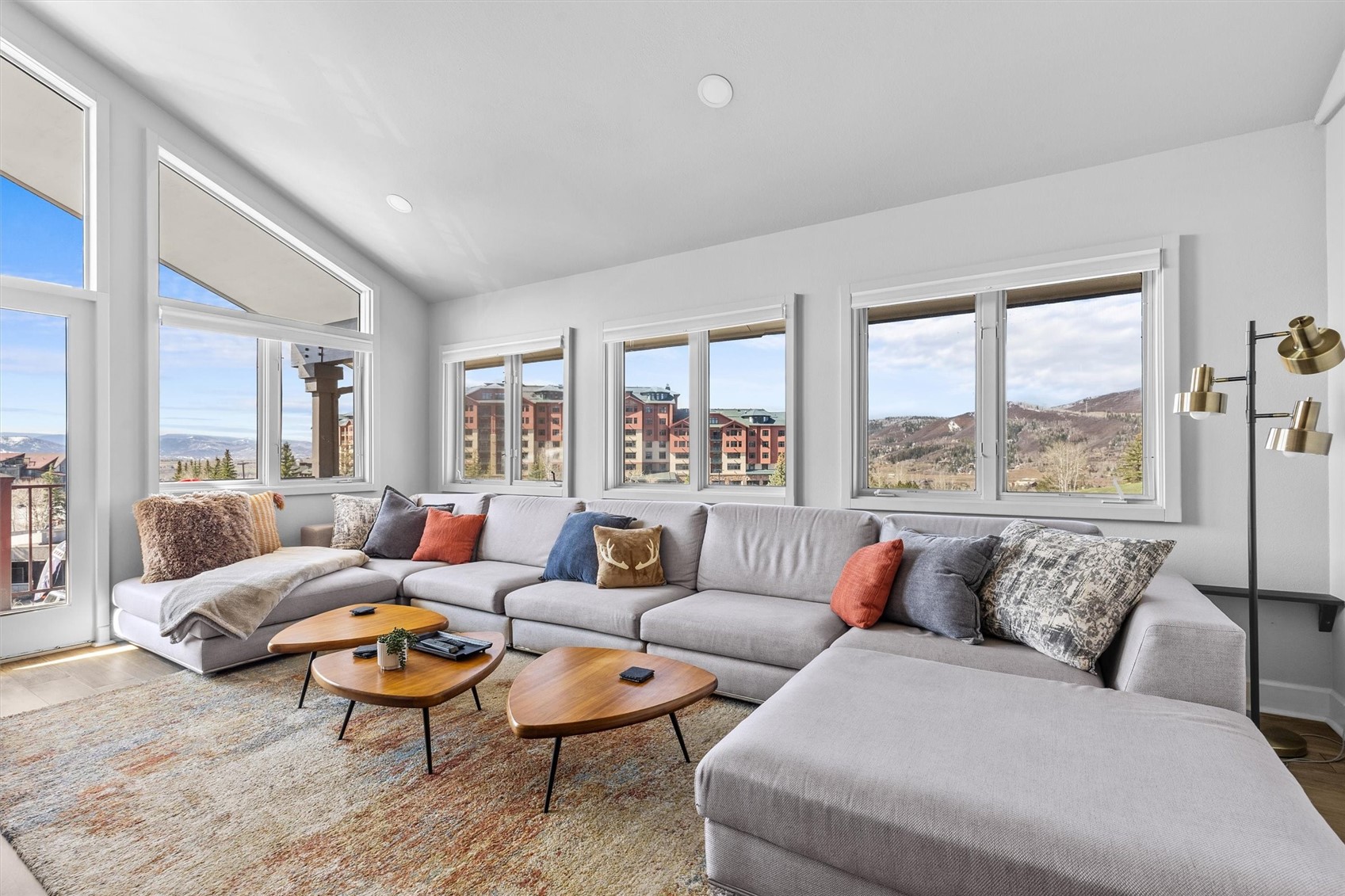 Living room with a gray sectional and wide windows overlooking the mountains.