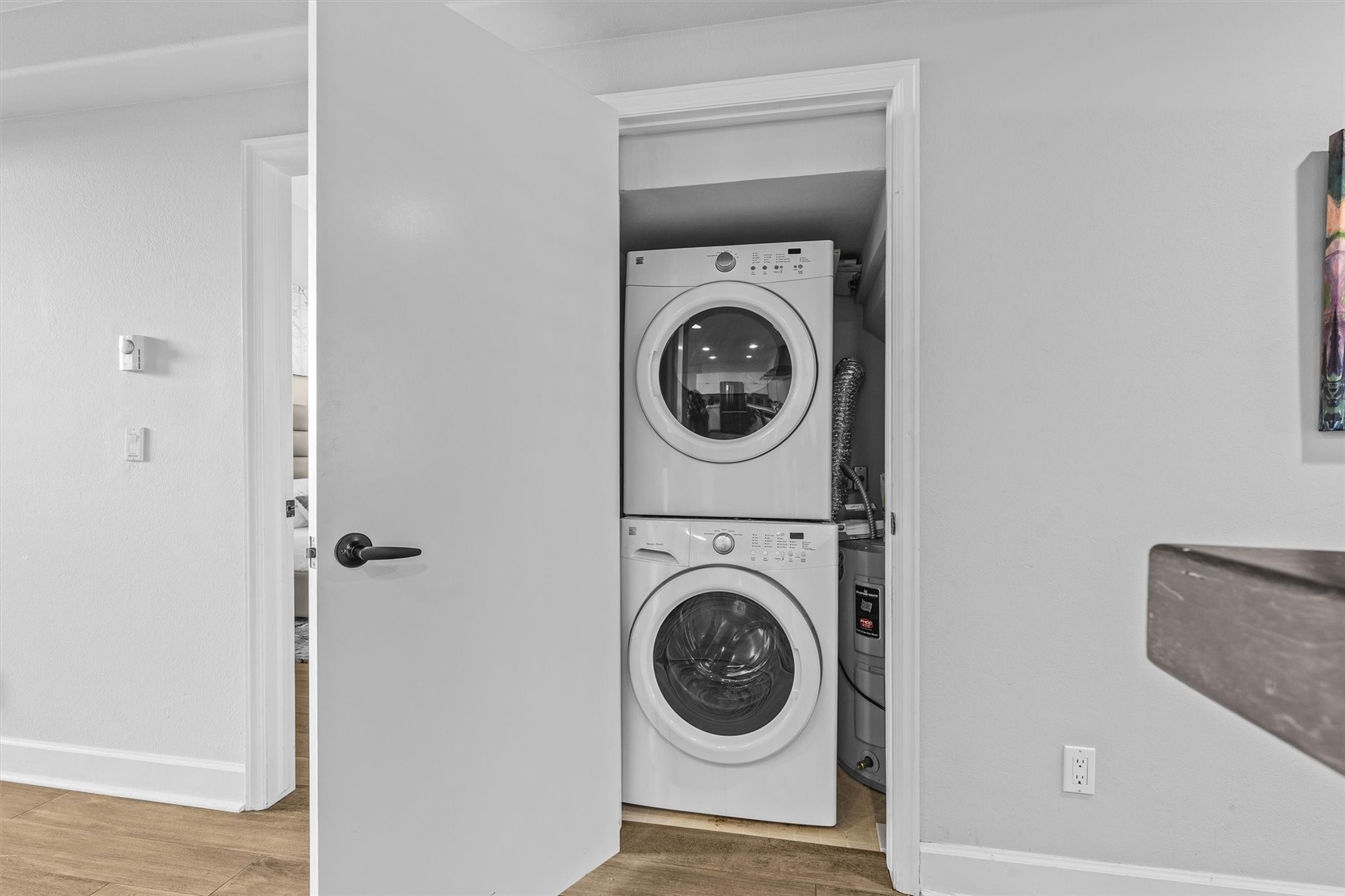 Laundry closet with stacked washer and dryer beside a water heater.