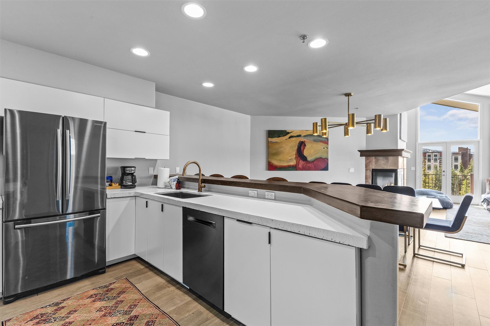 Open-plan kitchen with white cabinets, a stainless refrigerator, and a long dark wood breakfast bar.