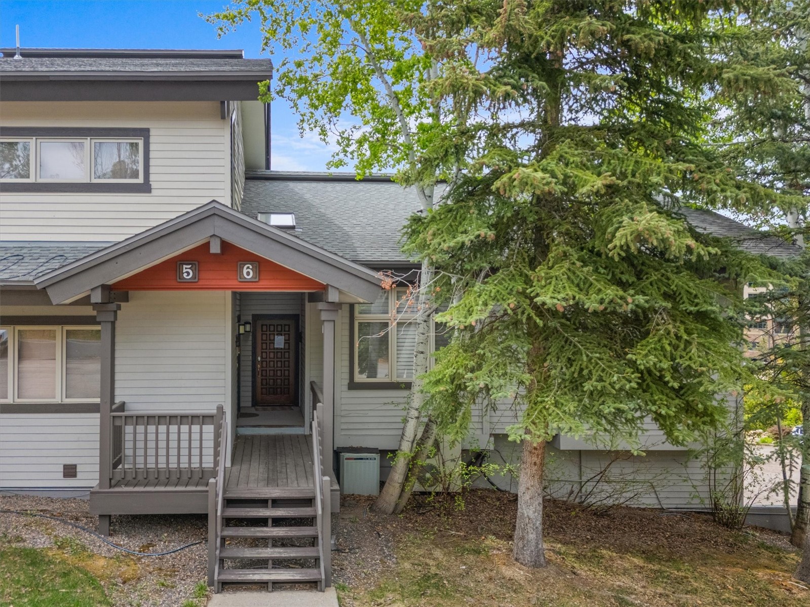 Townhouse entrance with wooden steps, unit numbers 5 and 6, and mature trees.
