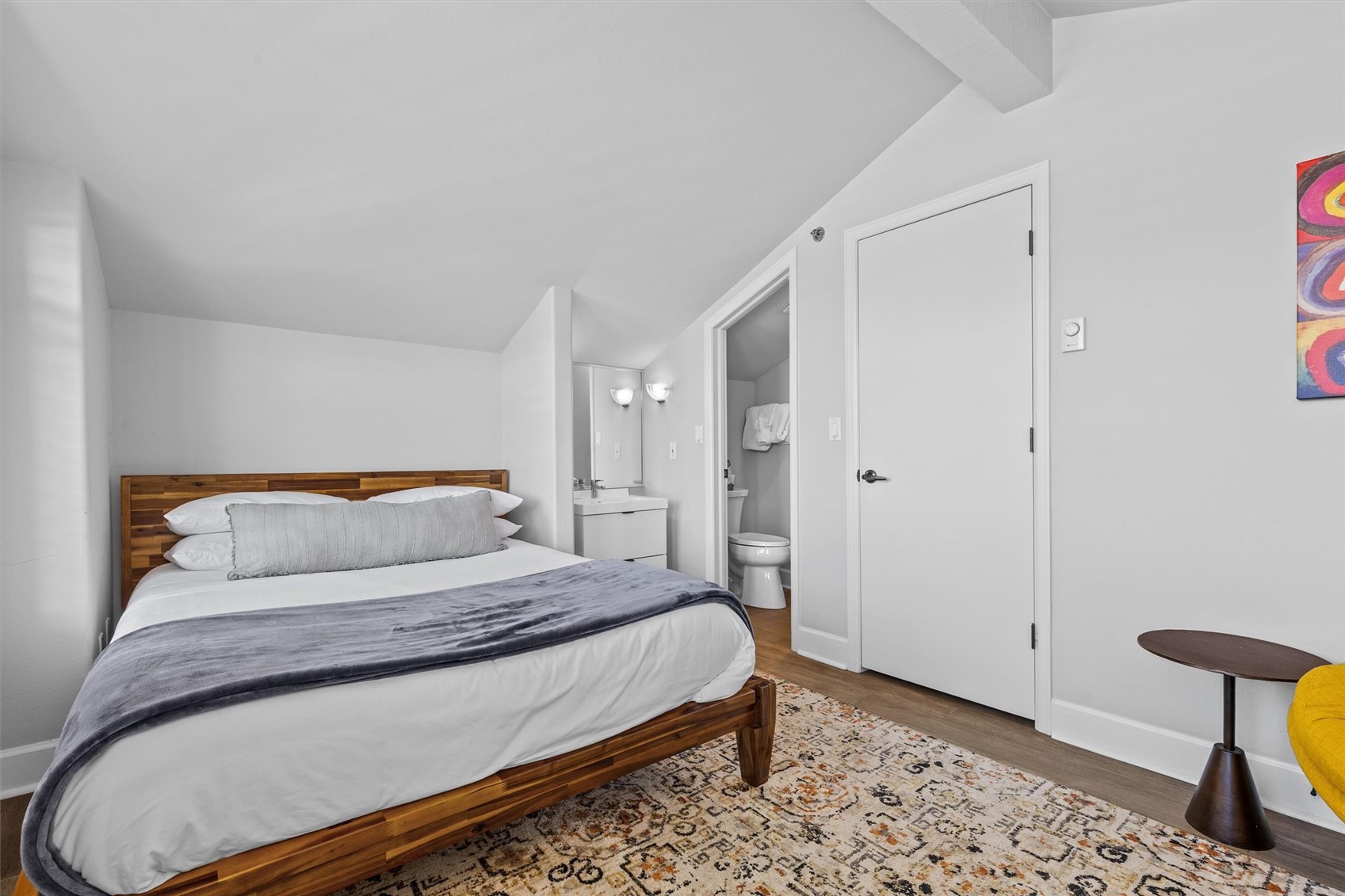 Bedroom with a wooden platform bed and an open doorway to an adjoining bathroom.