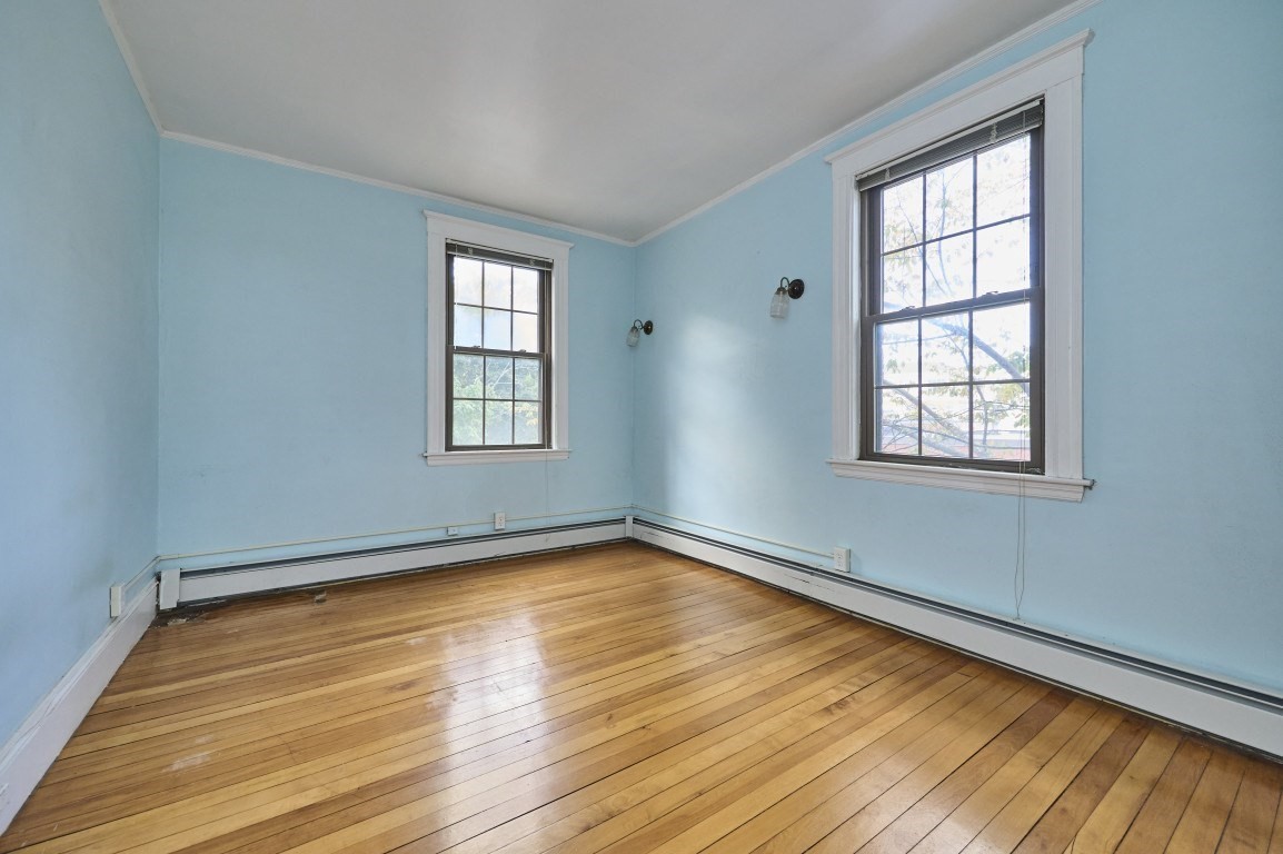 Empty blue-walled room with two tall windows and polished hardwood floors.
