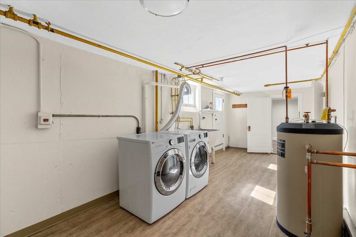 Basement laundry room with a front-loading washer and dryer beside a large water heater.