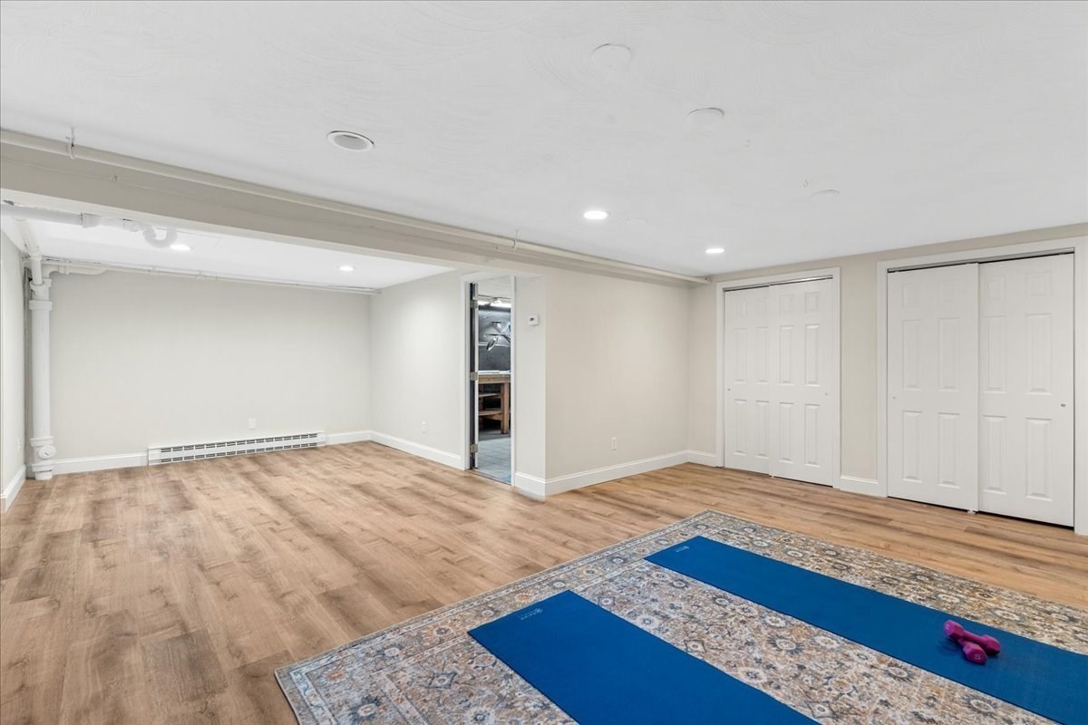 Basement exercise room with two blue yoga mats and pink hand weights on a patterned rug.