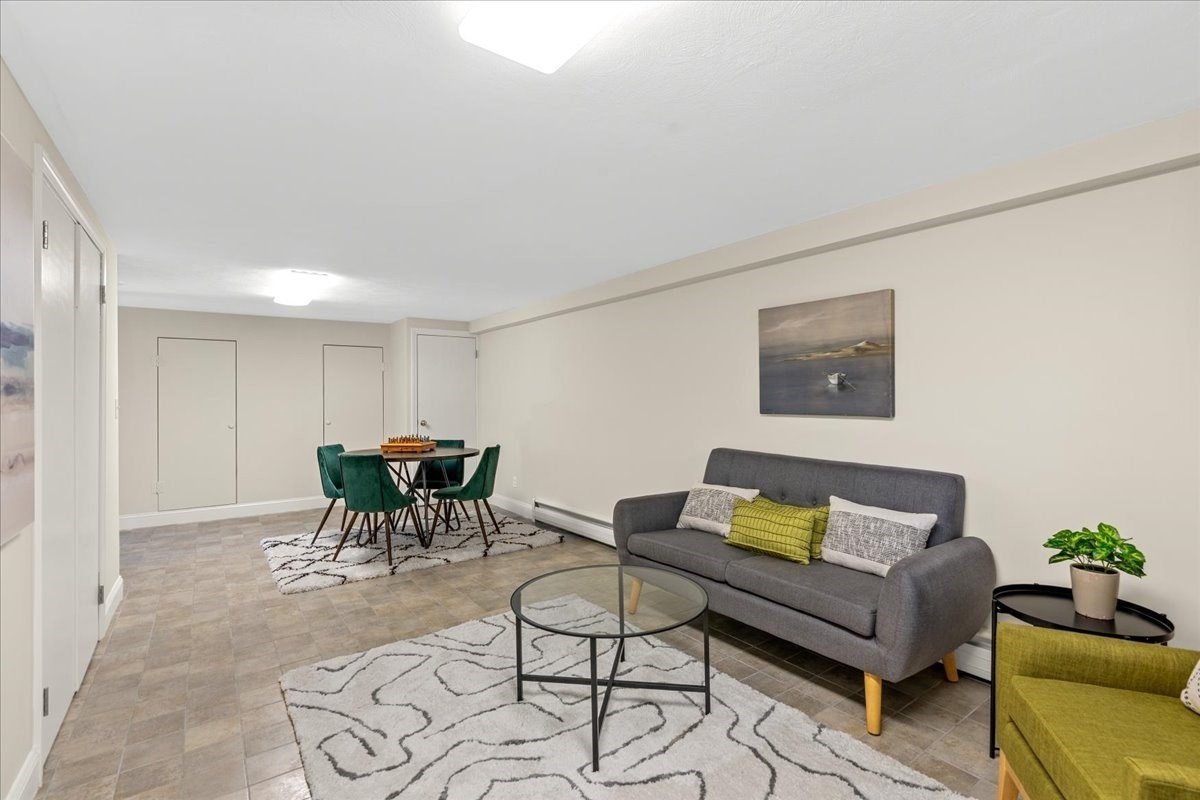 Furnished living and dining area with a gray sofa, glass coffee table, and round dining table.