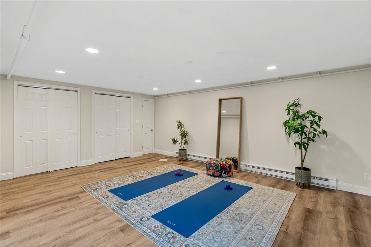 Exercise room with two blue yoga mats, a patterned rug, leaning mirror, and potted plants.