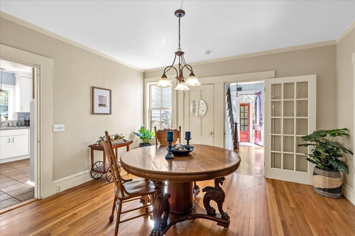 Dining room with a round wooden table, hardwood floors, and glass-paneled doors.