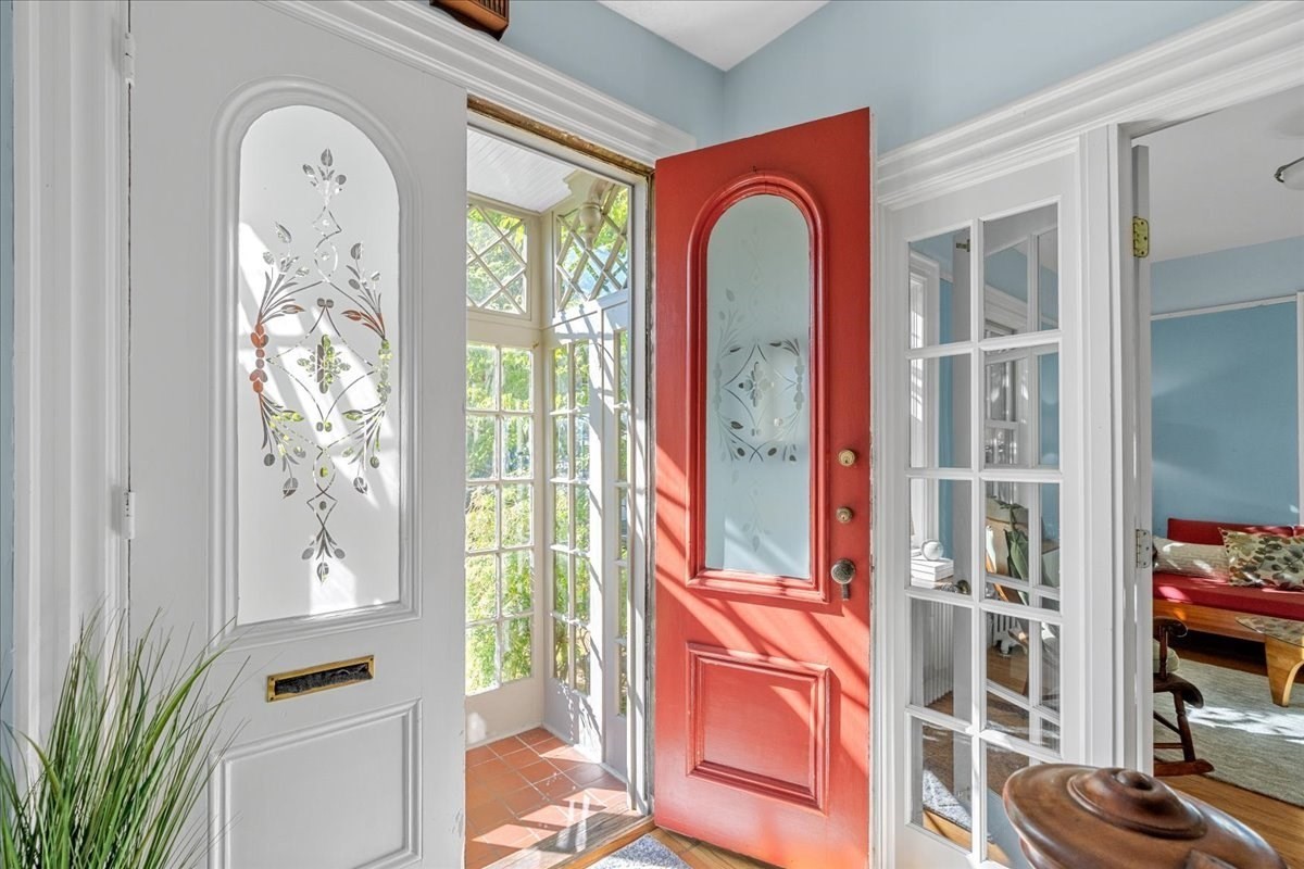 Front entry with a red door, decorative-glass door, and sunlit tiled vestibule.