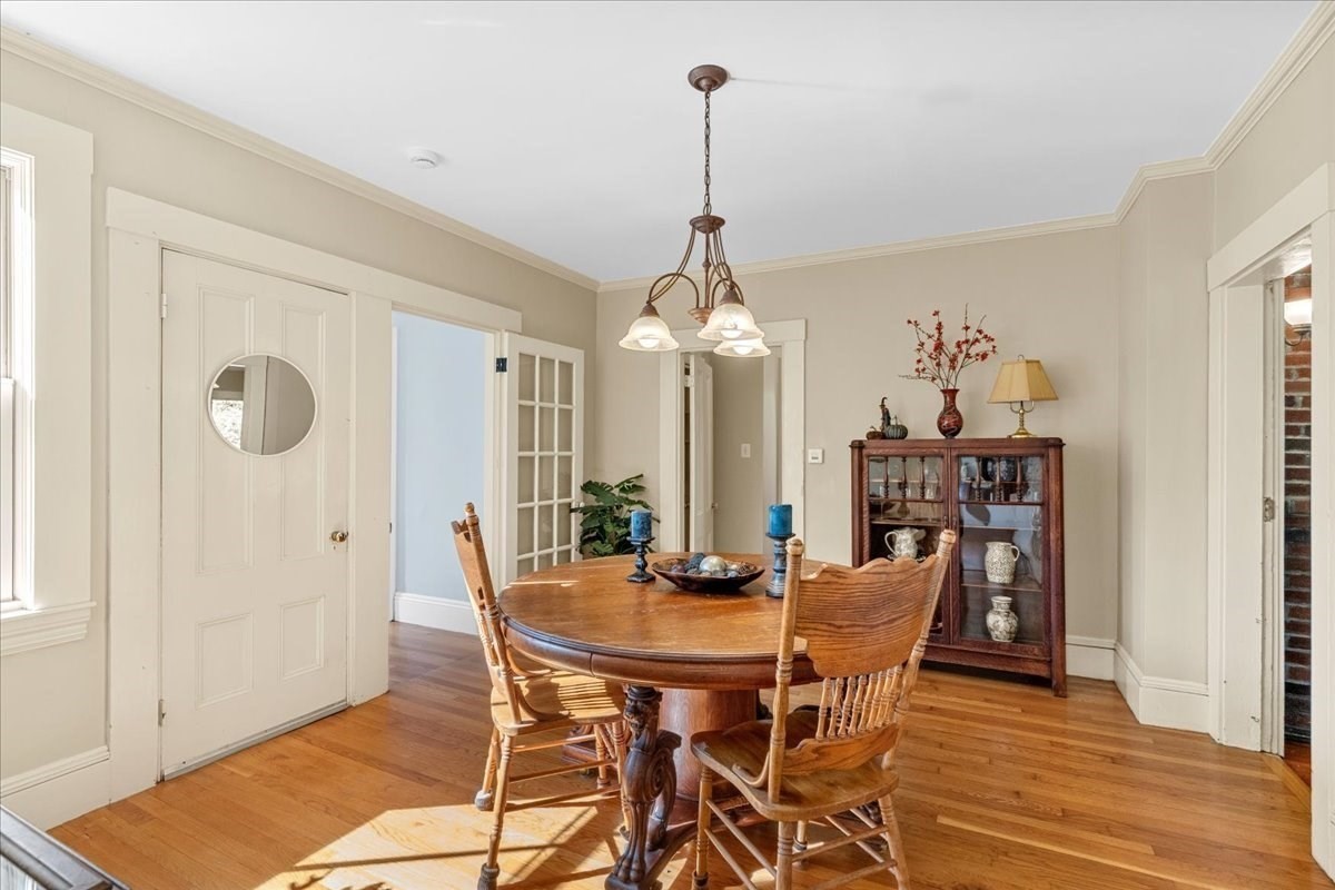 Dining room with an oval wooden table, spindle-back chairs, and a glass-front china cabinet.