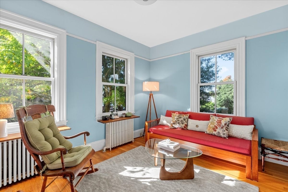 Living room with a red sofa, green-cushioned wooden chair, and tall windows.