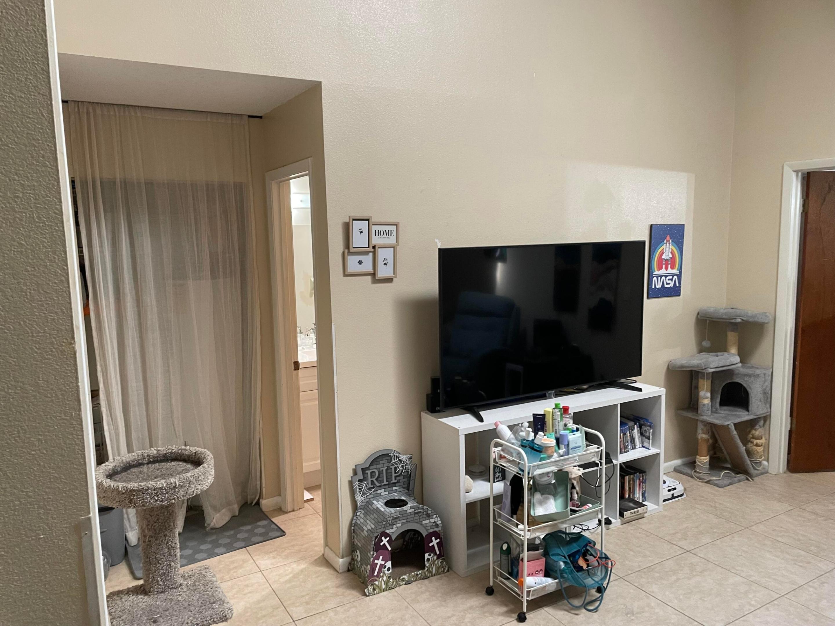 Living room with a large television, white cubby stand, and several cat trees.