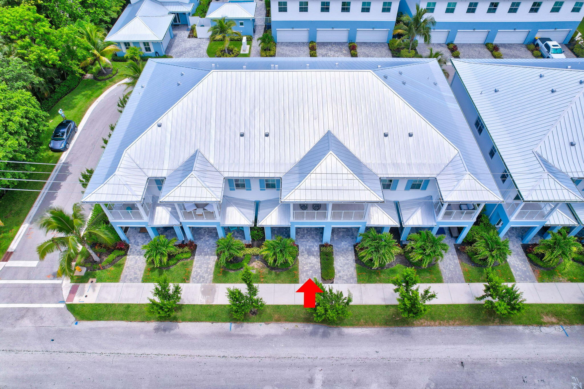Aerial view of blue townhomes with a red arrow marking one unit.