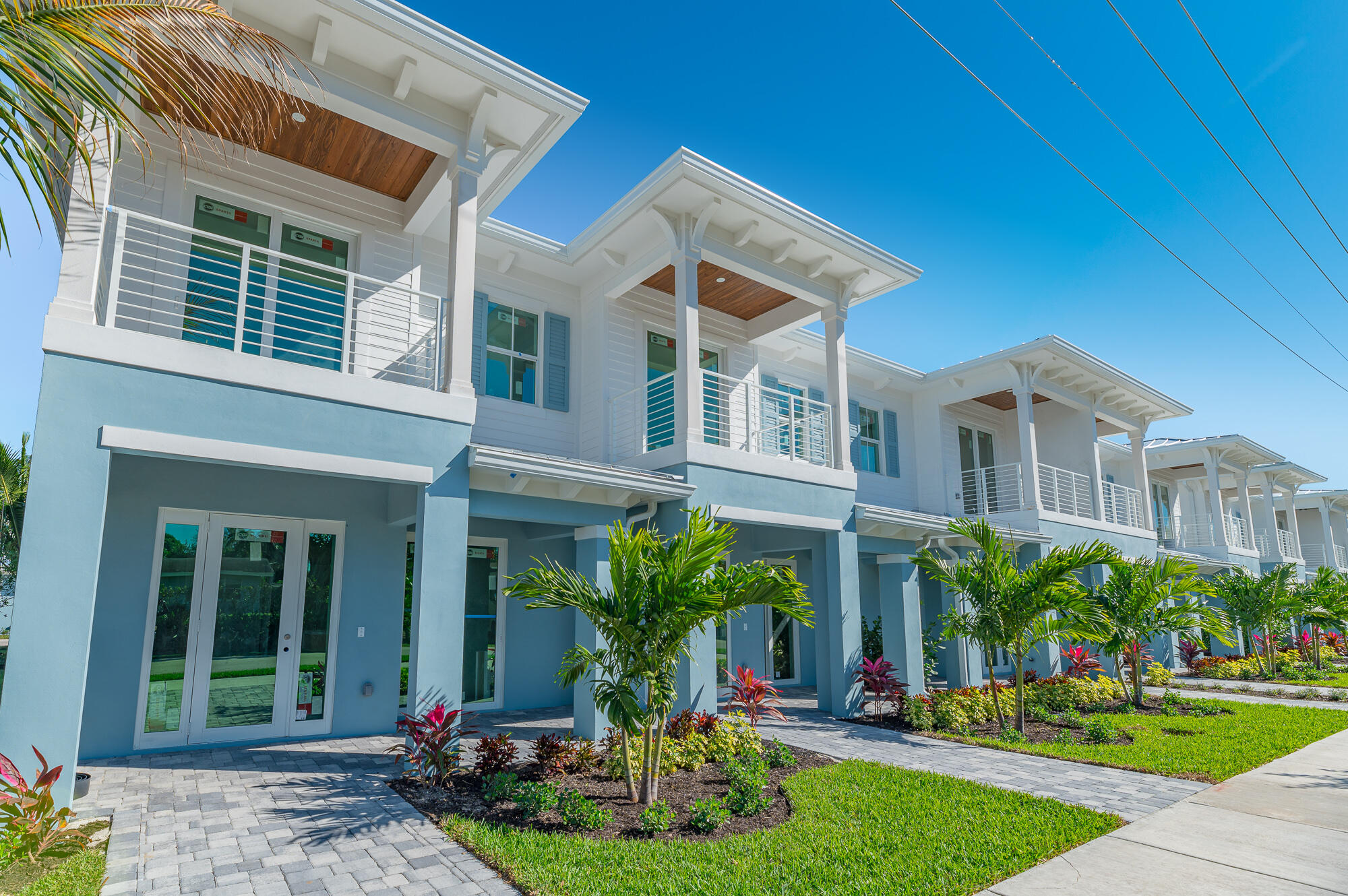 Modern coastal homes with covered balconies, tropical landscaping, and paved walkways.