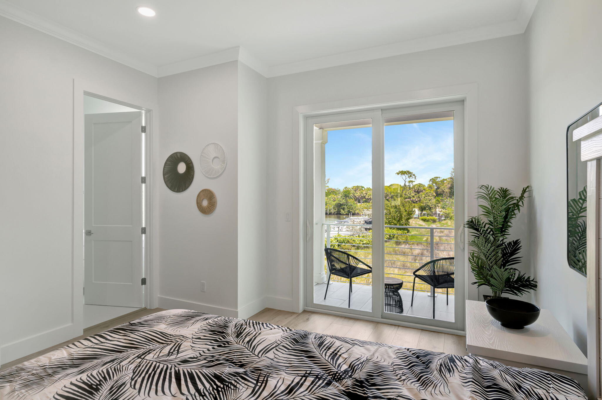Bedroom with patterned bedding and sliding doors opening to a balcony overlooking water and boats.