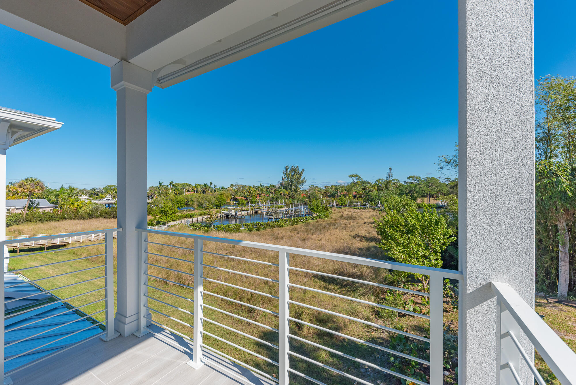 Covered balcony overlooking a grassy marsh and marina with boat docks.