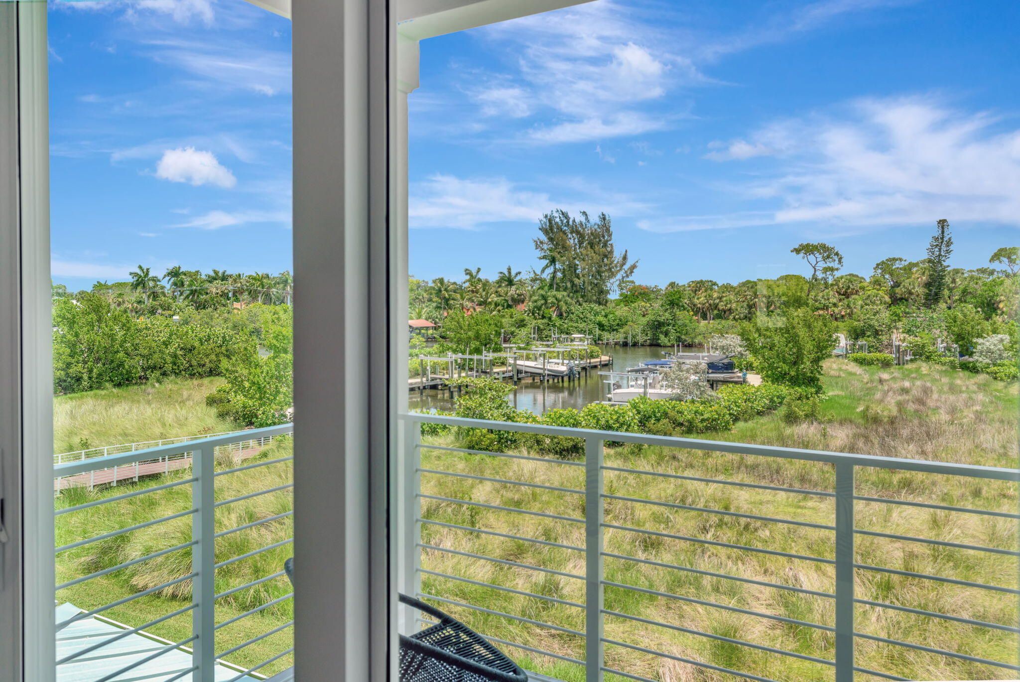 Balcony overlooking a canal with boat docks and boats, framed by large windows.