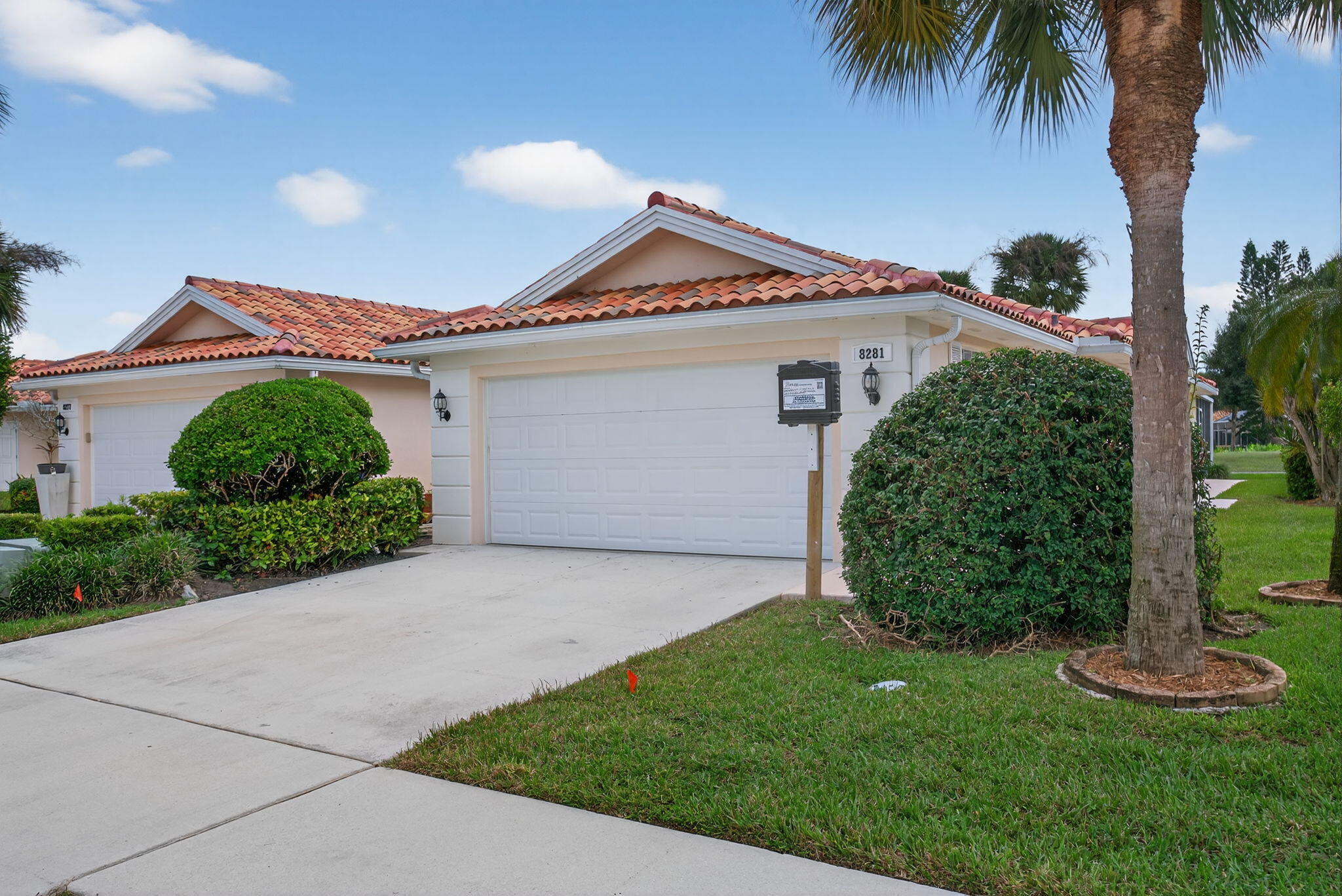 Single-story home with a terracotta tile roof, double garage, and landscaped tropical yard.