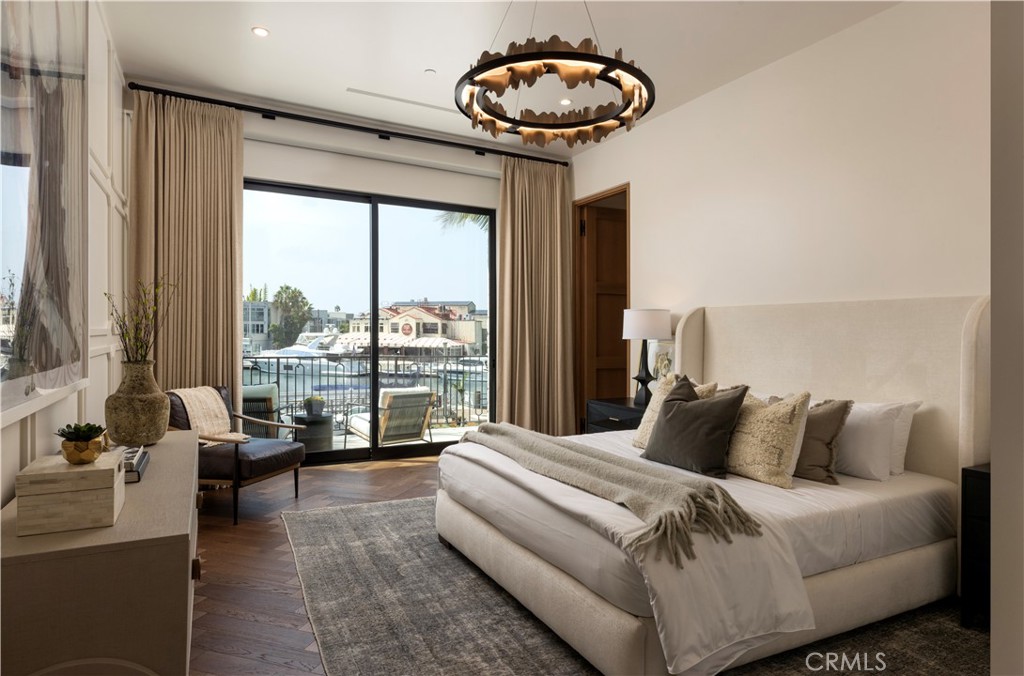 Staged bedroom with a king-size bed and sliding doors overlooking a marina.