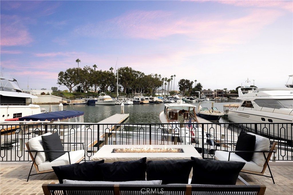 Waterfront patio with a fire pit and cushioned seating overlooking a marina.