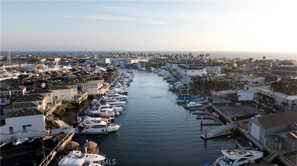 Aerial view of a Newport Beach marina lined with homes and boats at golden hour.