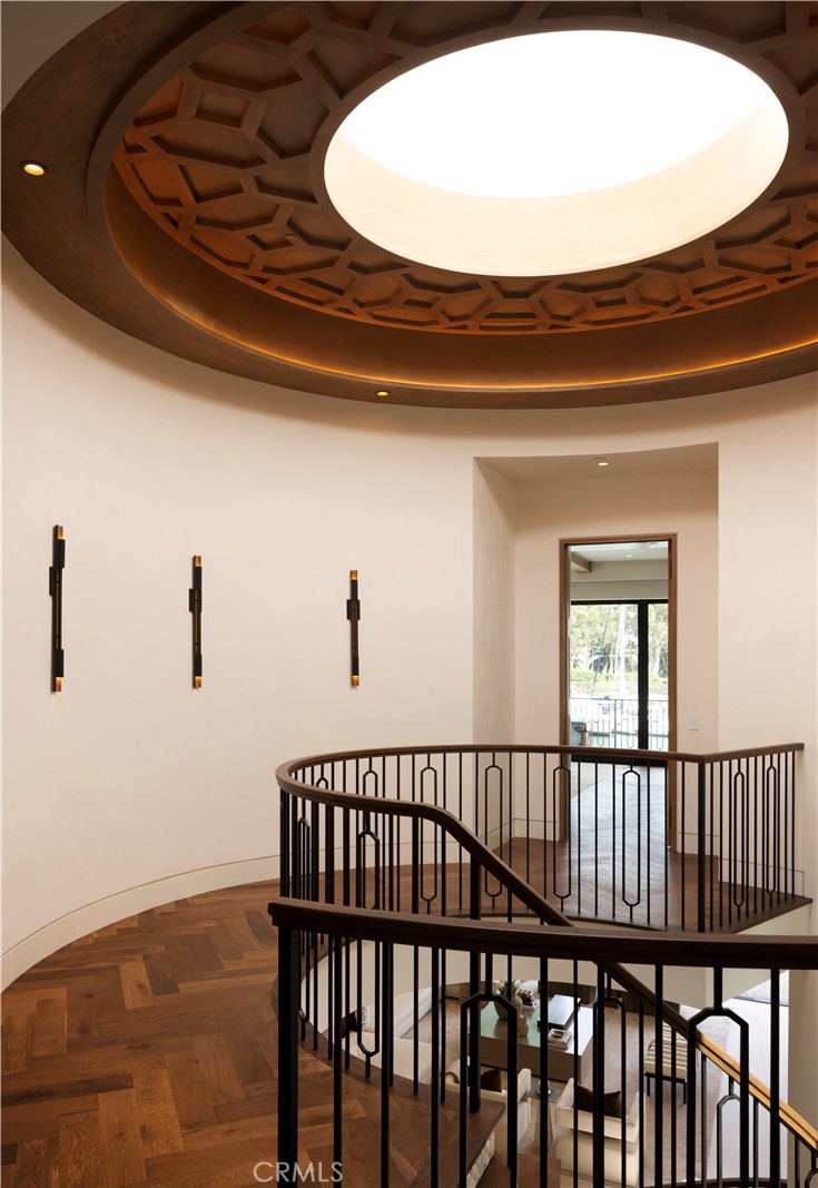 Curved staircase landing beneath a circular coffered wood ceiling and large skylight.