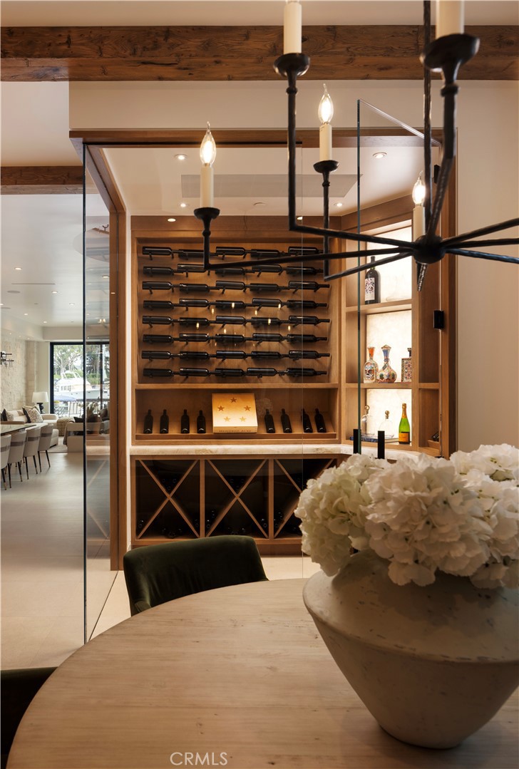 Built-in wine cellar with illuminated bottle racks beside a dining table and flower arrangement.