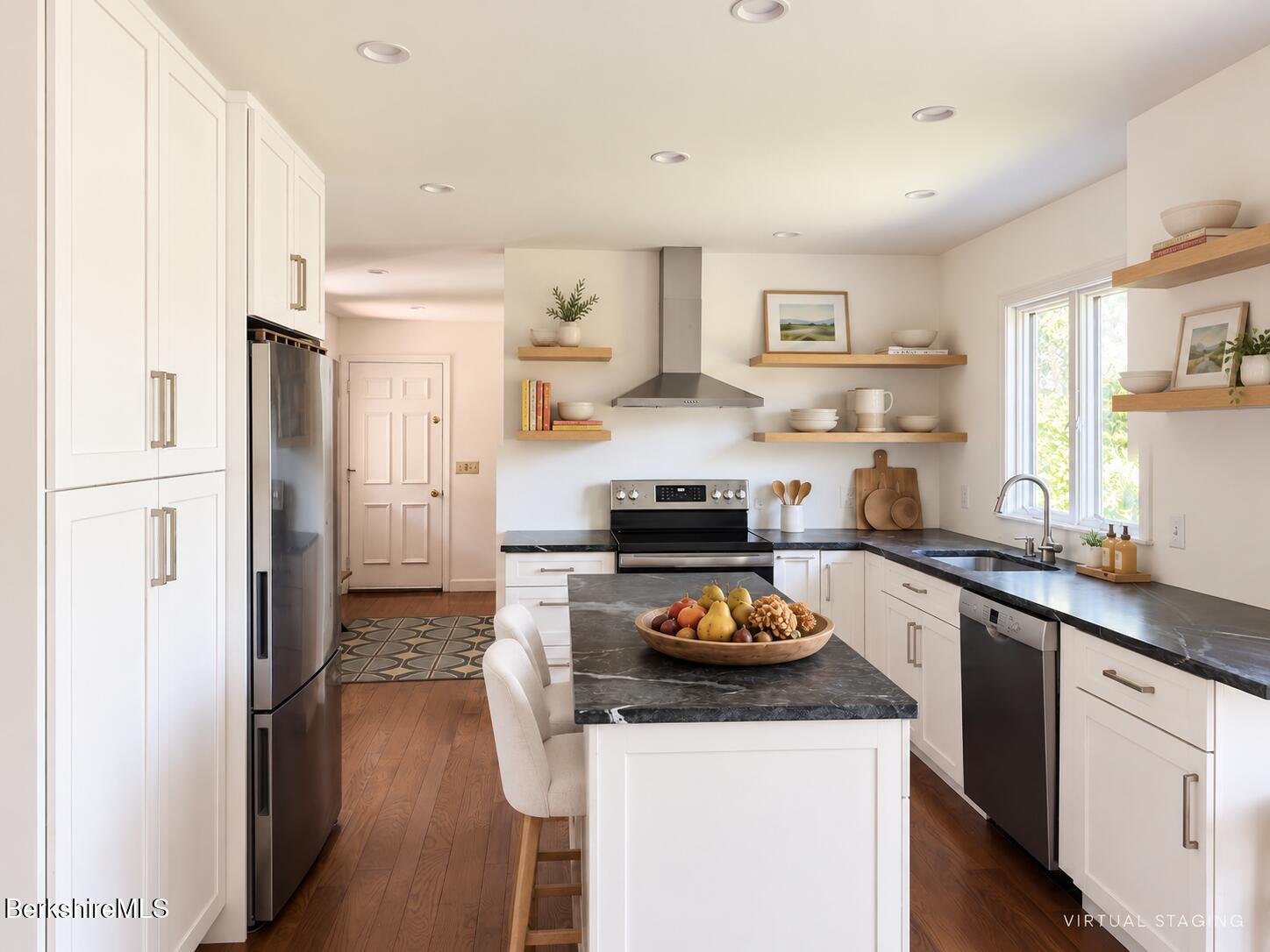 Kitchen with white cabinetry, dark marble counters, a central island, and stainless steel appliances.