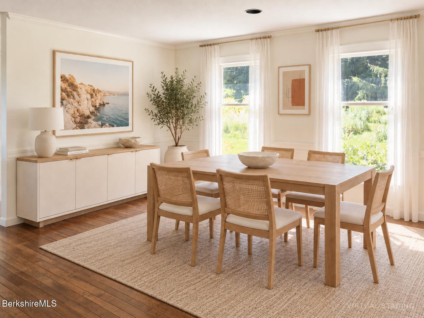 Dining room with a wooden table, cane-back chairs, cream sideboard, and tall curtained windows.