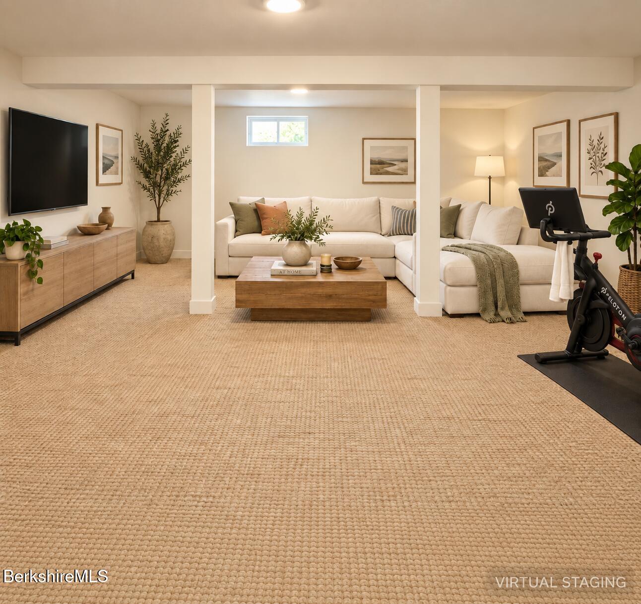 Virtually staged living room with a white sectional, wall-mounted TV, and exercise bike.