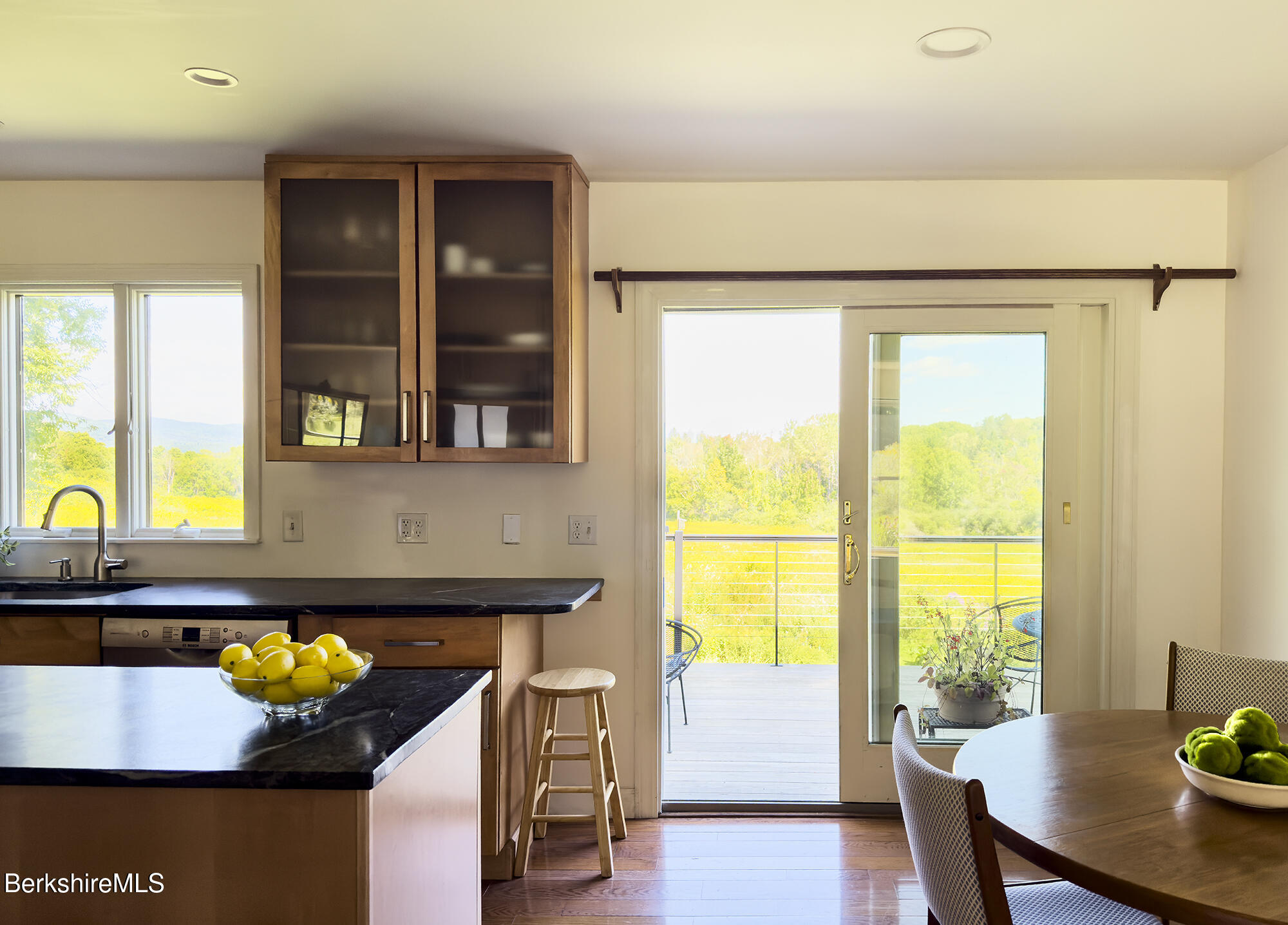 Kitchen with dark stone counters and sliding doors opening to a deck and green countryside.
