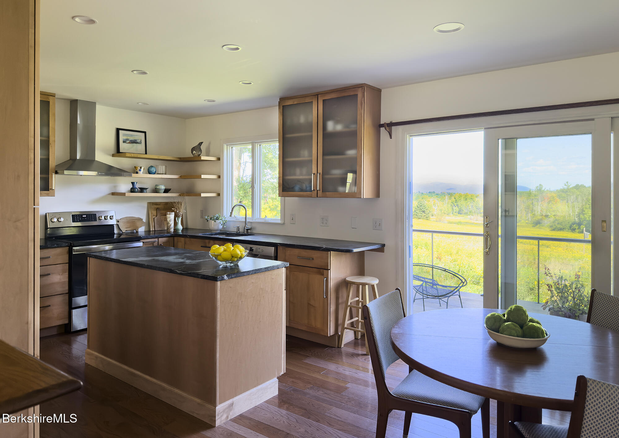 Kitchen and dining area with a wood island and sliding doors opening to a deck and wooded views.