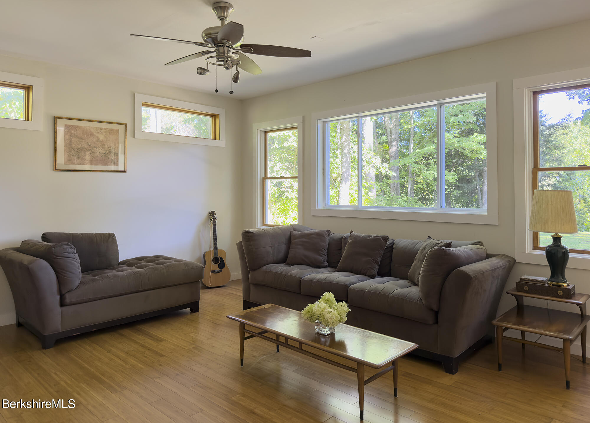 Living room with two brown sofas and large windows overlooking trees.