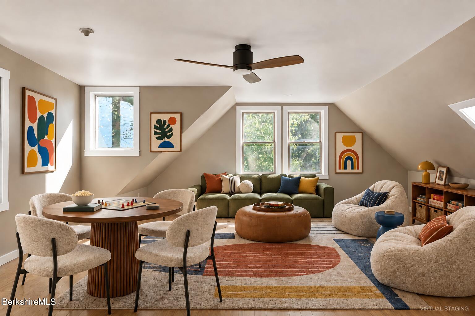 Staged living room and dining area with a green sofa, round table, and sloped ceiling.