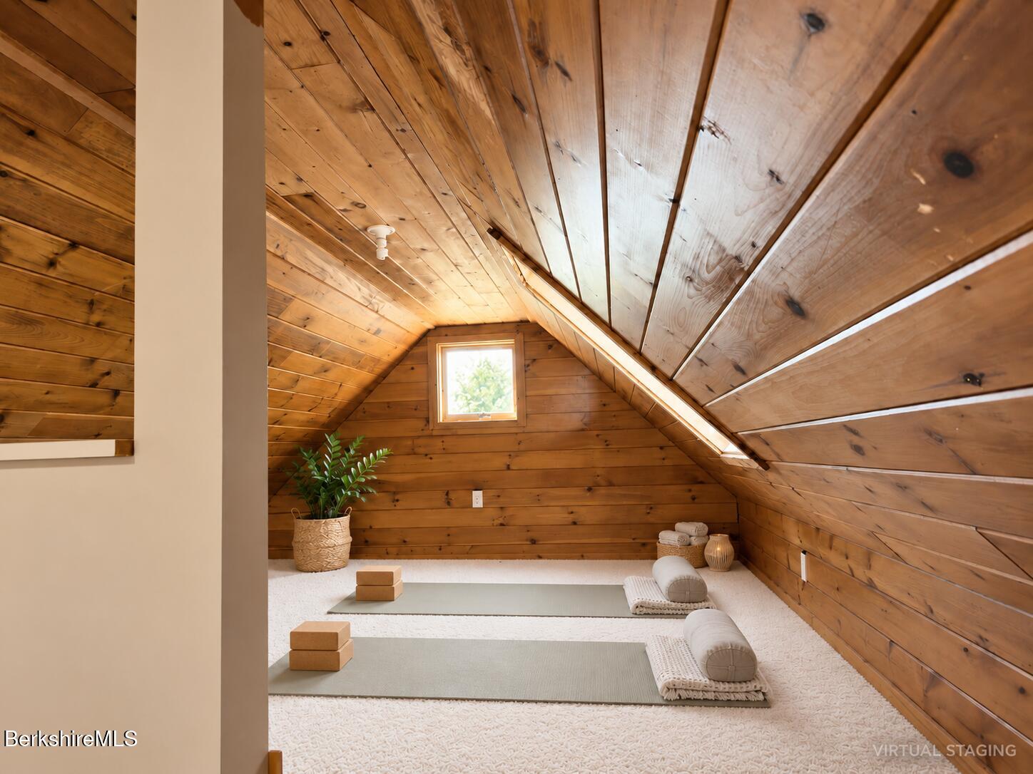 Attic yoga room with sloped wood-plank ceiling, two mats, and a small window.