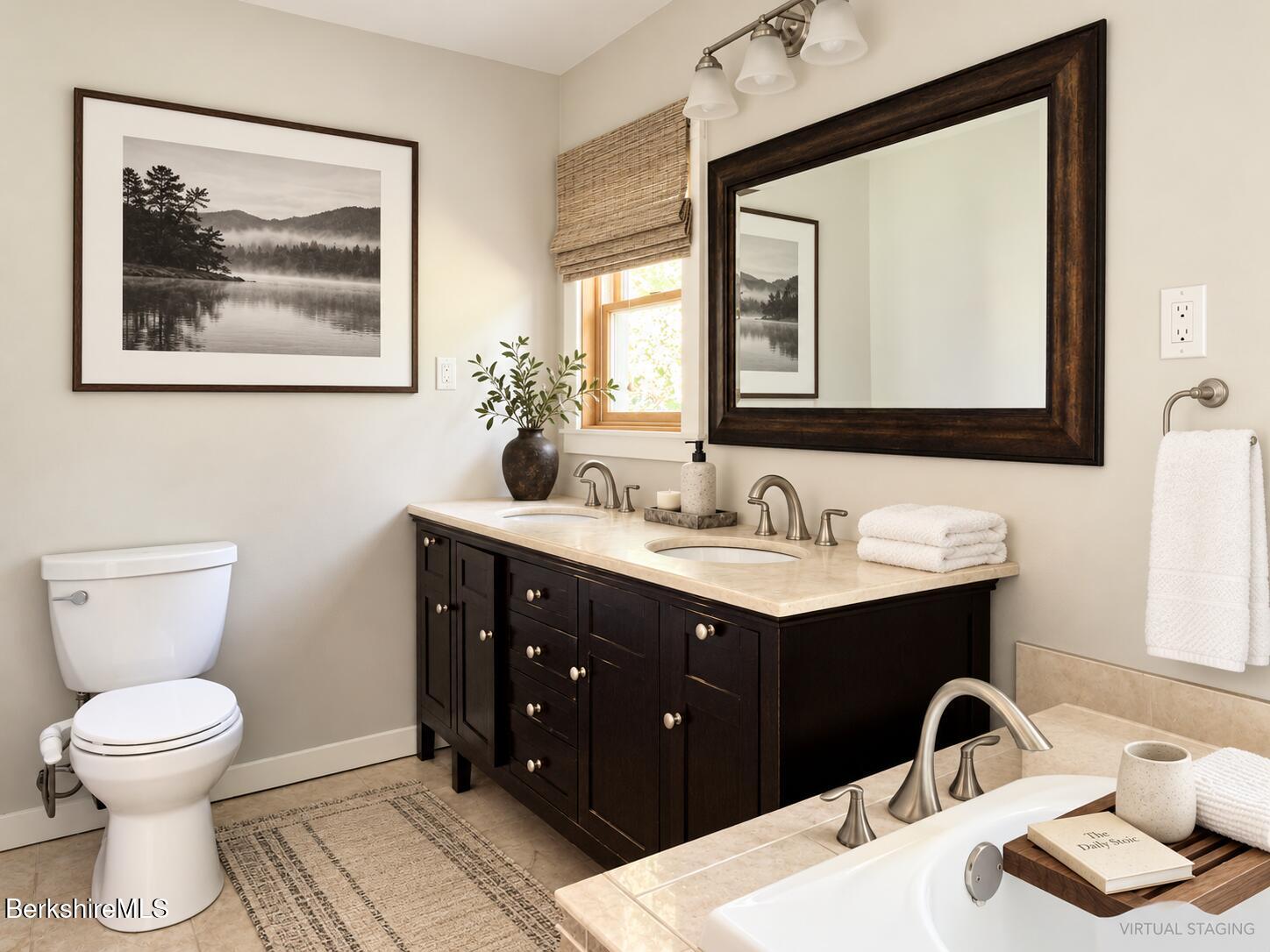 Bathroom with a dark wood double-sink vanity, large framed mirror, and bathtub.